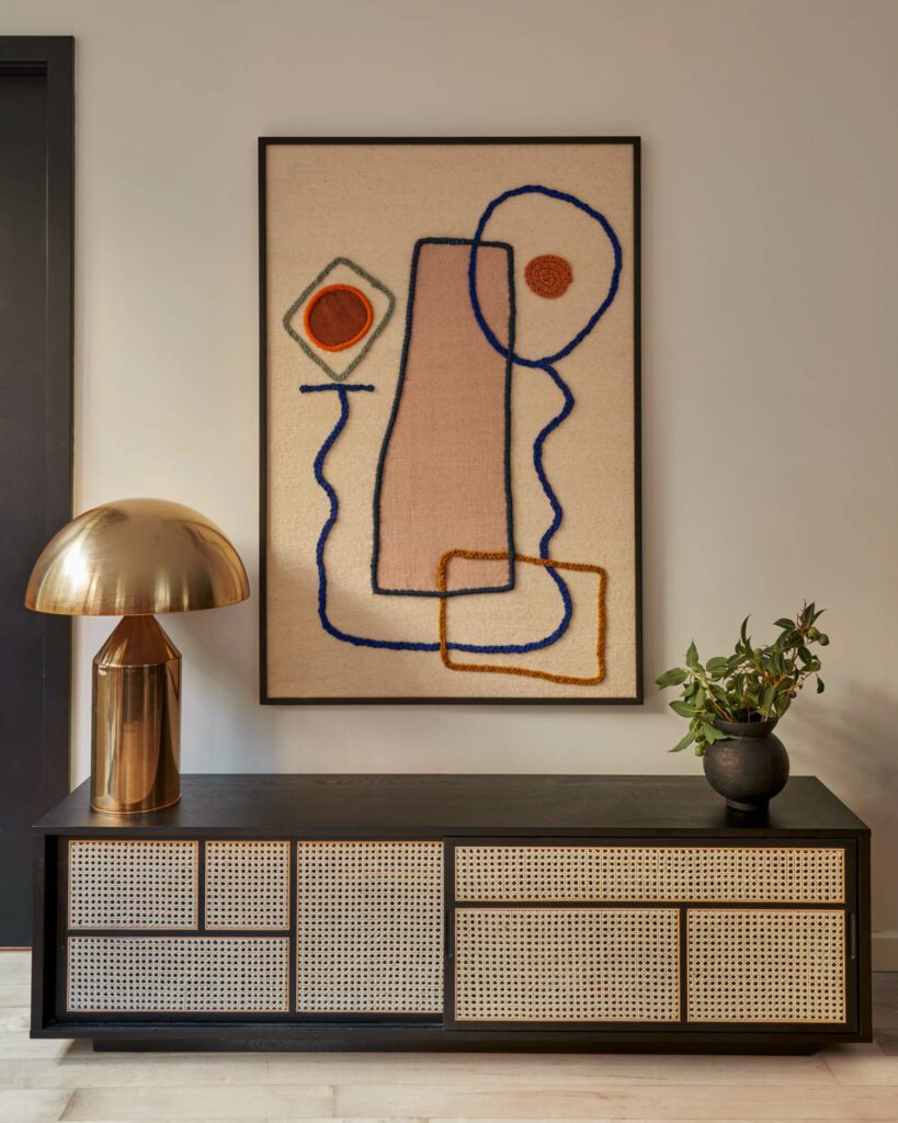 In the dining area, the artwork over the Industry West console is by LRNCE and the table lamp is by Sit Down NY.