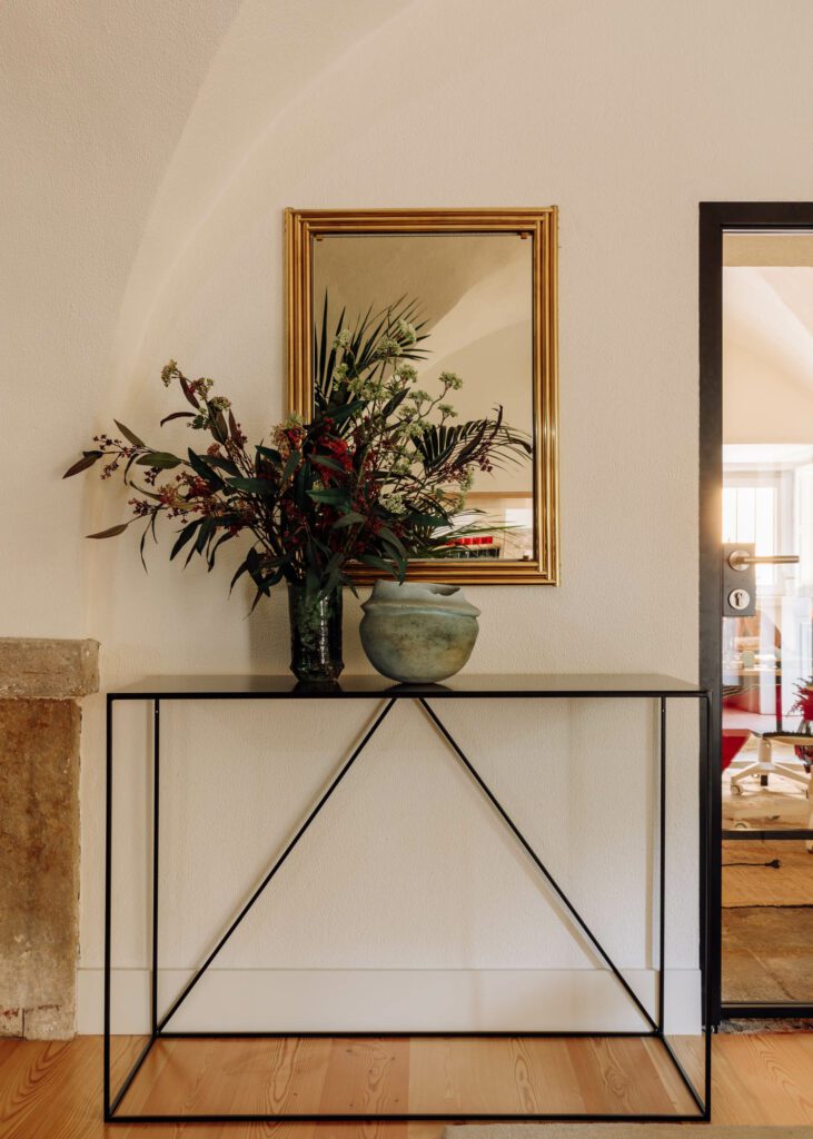 Flowers reflect in a mirror above a console table by Le Redoute.