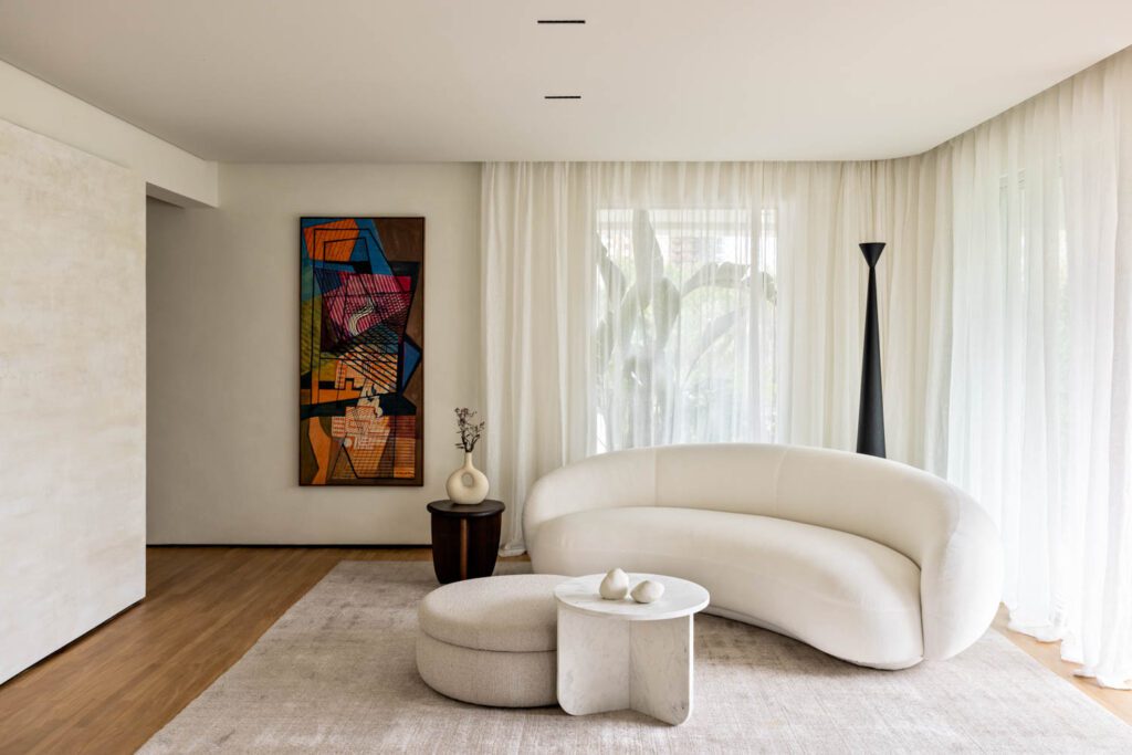 In the living room, a sofa by Jonas Wagell mixes with a marble coffee table by Estudio Rain and a hardwood side table by Estúdio Orth, while the artwork is by Roberto Burle Marx. 