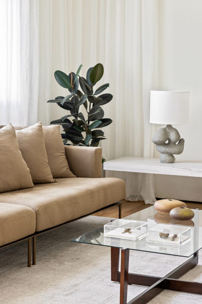 A lamp by Juliana Nagle Atelier rests on a vintage 1950’s table through Loja Teo in a corner of the living room, near a Fillet sofa by EstudioBola.