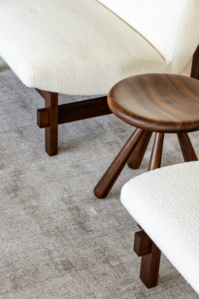 A wood stool designed by Alfio Lisi rests on a viscose rug from Clatt.