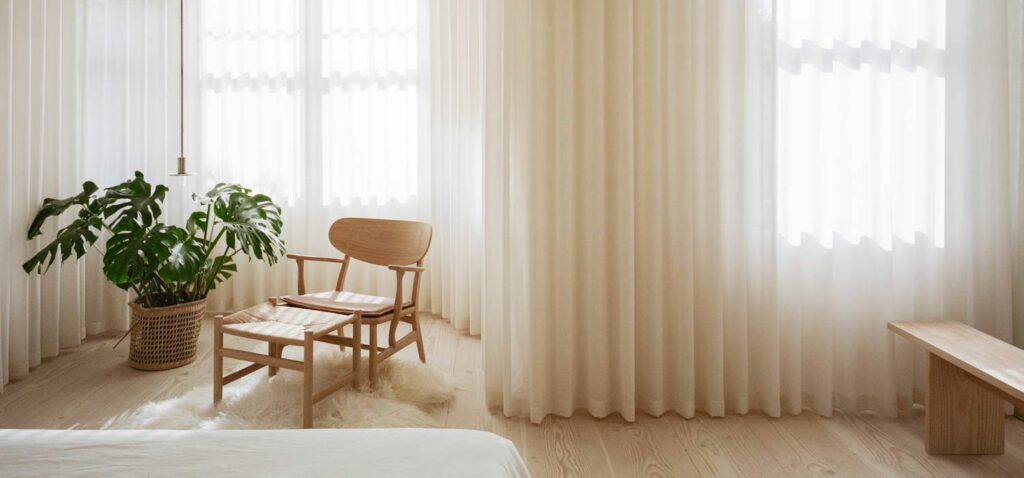 Drapes by The Hackney Draper define the primary bedroom, with a Viabizzuno pendant and Carl Hansen pendant.