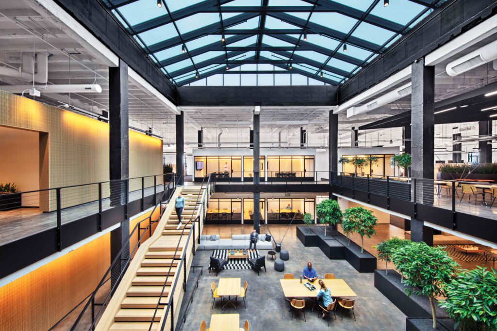 Also new is the glass roof above another atrium, where oak-finished engineered wood forms the stairs and ribbed acoustic bamboo panels some walls.