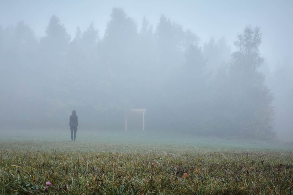 a foggy field with a pavilion in the center