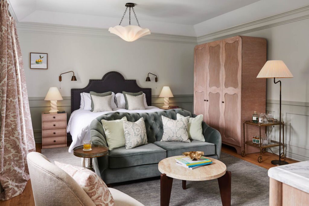 One of the refined guest suites features white, plaster sculptural lamps by Sydney-based interior designer Lucy Montgomery, curved wooden furnishings and a velvet love seat.