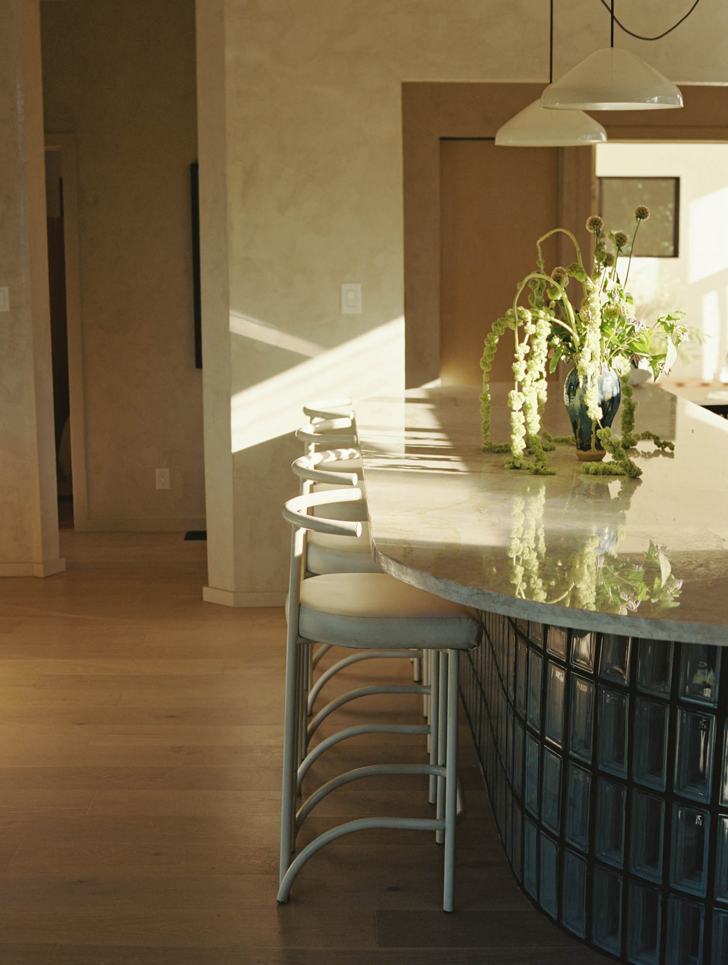 OWIU playfully integrates glass privacy blocks as the base of the bean-shaped kitchen counter, allowing the fixture to seemingly float.