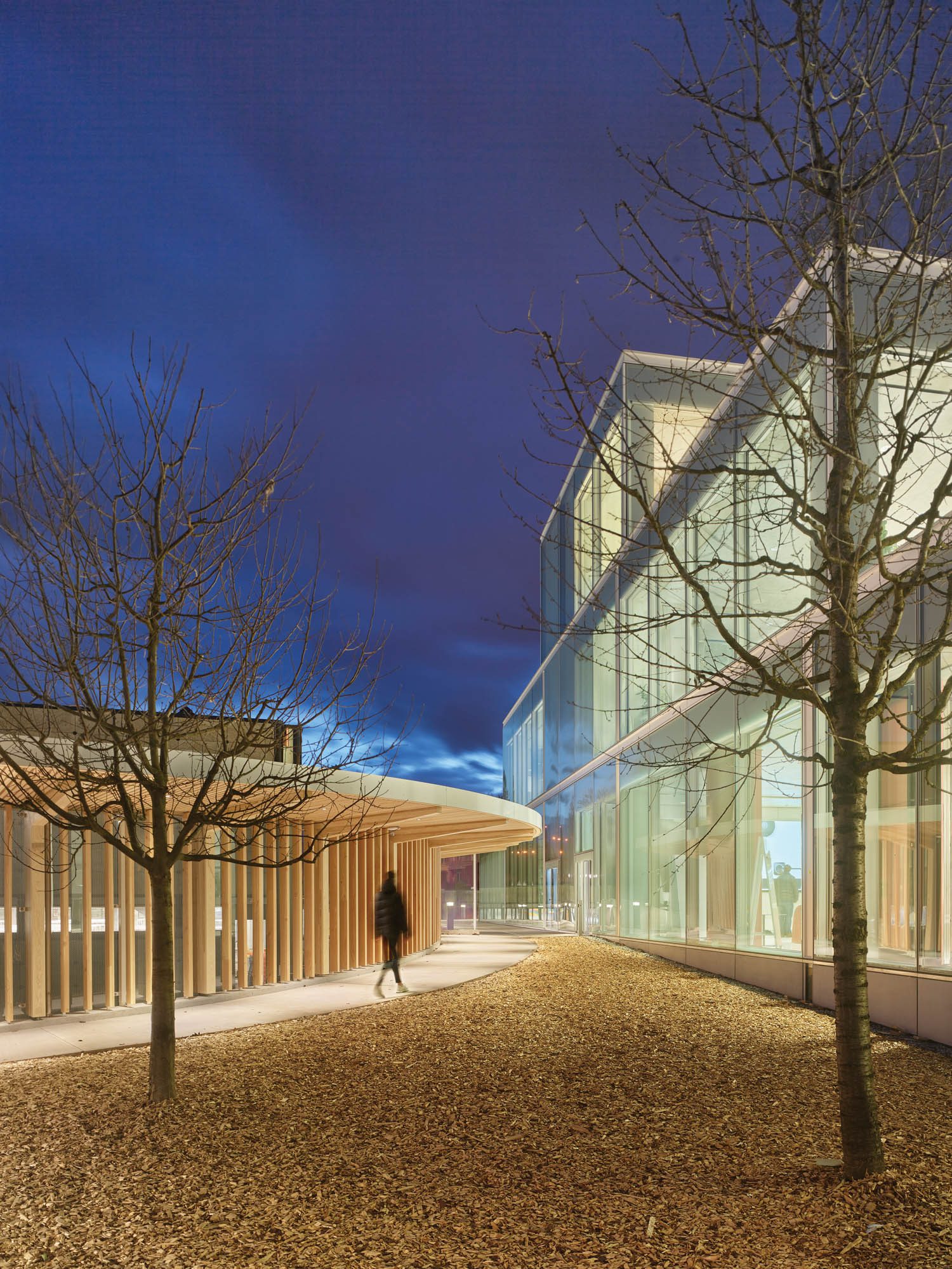 a person walks across the campus of HSG Learning Center SQUARE, University of St. Gallen, Switzerland at nighttime