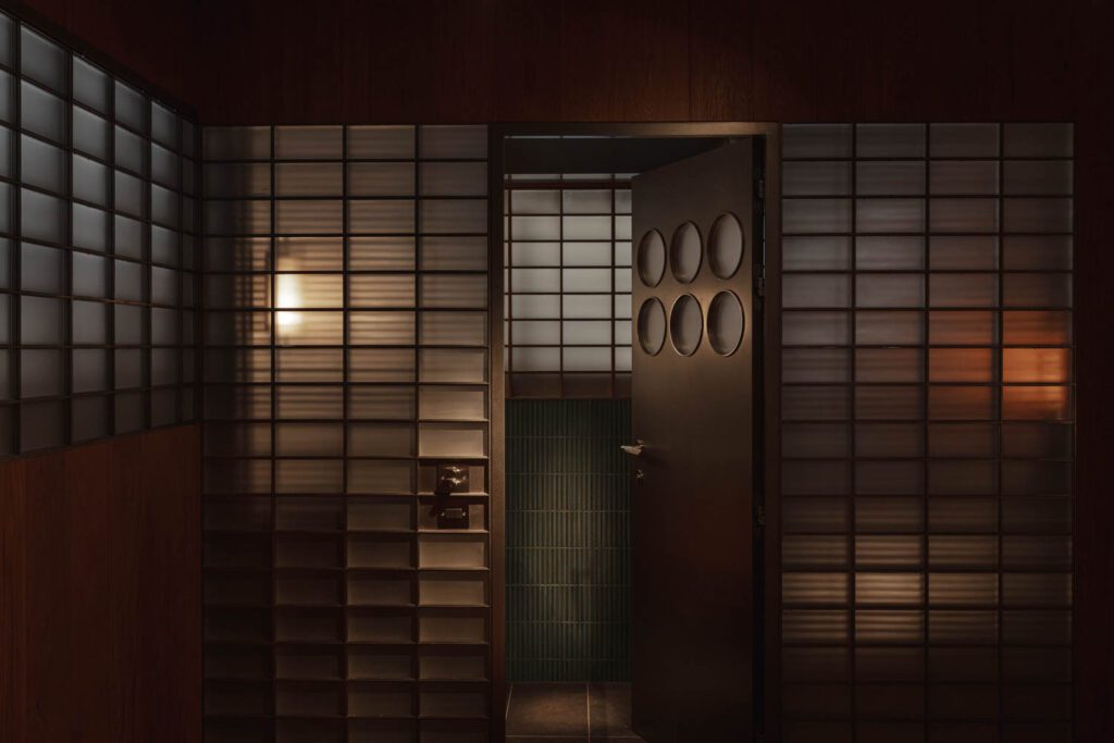 A screen of frosted glass bricks, and a door with frosted glass portholes, demarcates a bathroom.