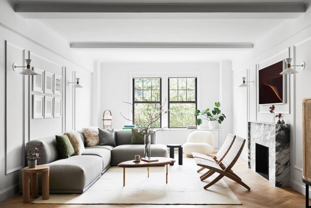 In the living room, a fireplace in BAS Stone Arabascato Ovulato marble warms a Muuto sofa, Pierre Paulin for Gubi swivel chair, and Carl Hansen & Søn chairs by Morten Gøttlerc.