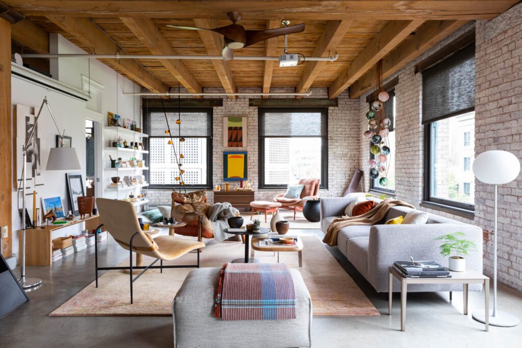 The living room features exposed brick, mismatched chairs and space for art and books.