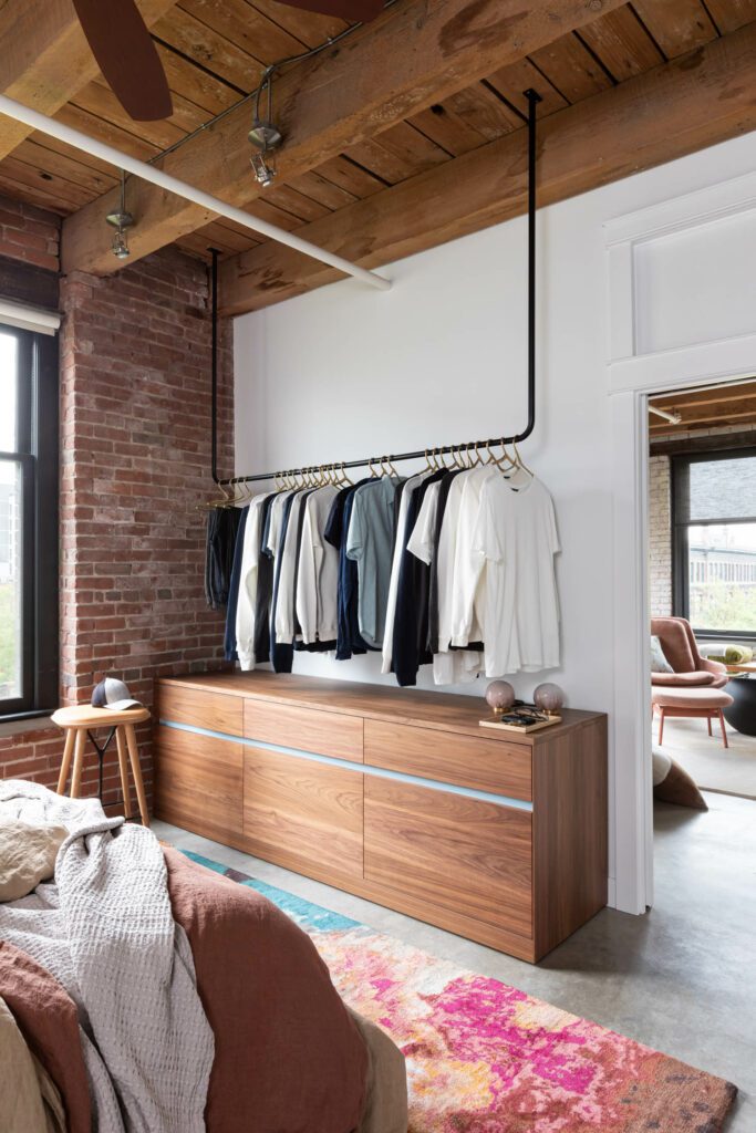 A custom dresser sits below a black hanging bar for the homeowner's clothes in the bedroom. 