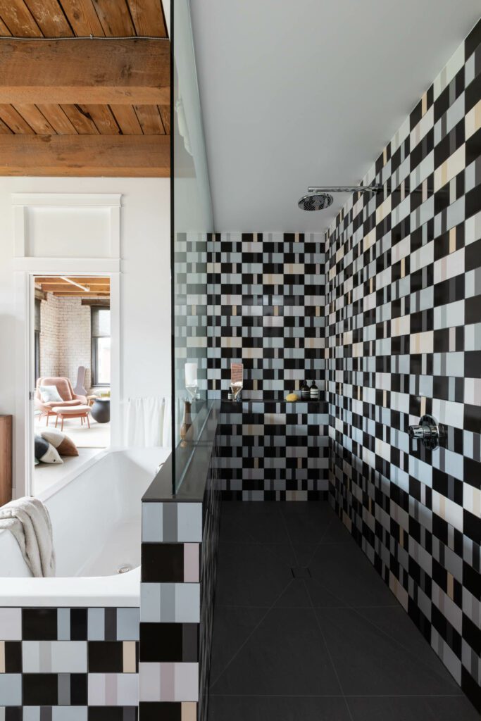 A black and white checkerboard wallcovering lines the shower wall and is also seen in the bath tiles. 