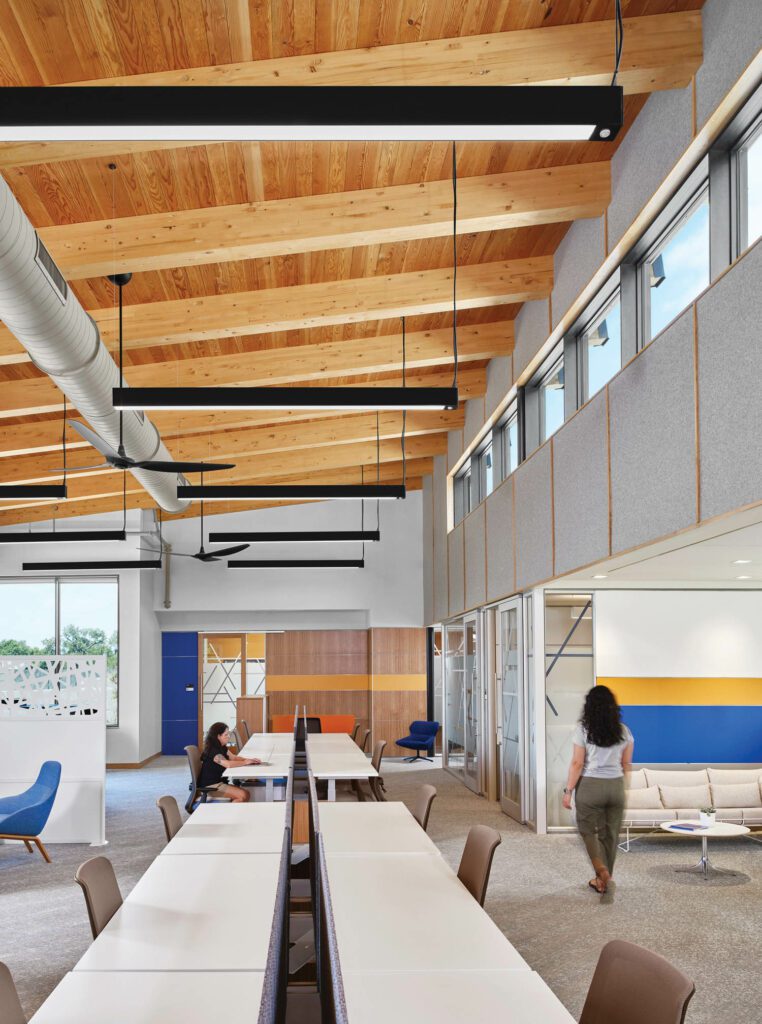 staff work at repurposed communal tables beneath clerestory windows