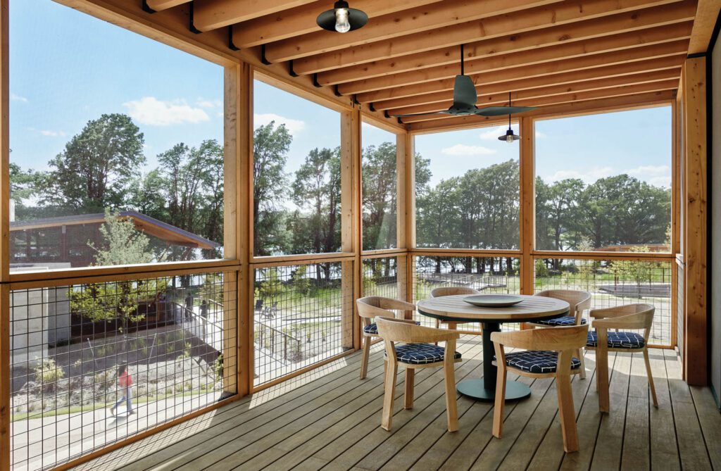 teak chairs and a table sit on the porch at the end of the hotel floor