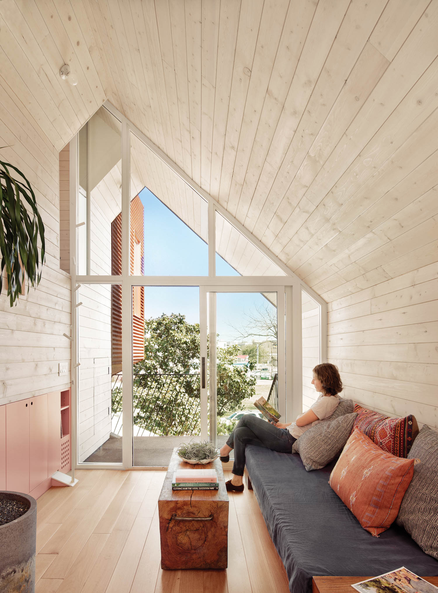 a woman sits in the living room with a large glass wall