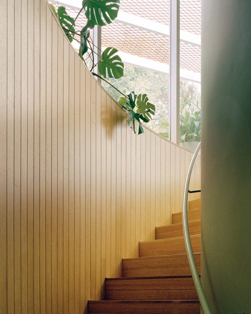 Victorian ash paneling defines the curved stair leading from the lounge to the primary suite.