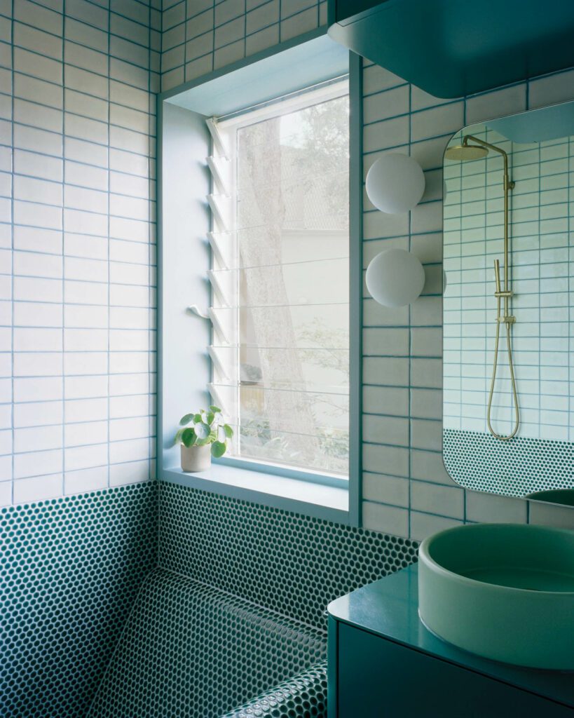 The kids’ bathroom features glazed ceramic tiles, brass taps, and a concrete basin.