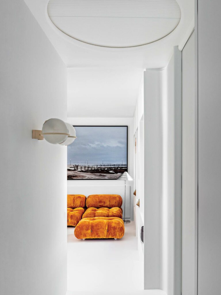 A vintage Gino Sarfatti sconce marks entry to the kids’ lounge, where Gian Maria Tosatti’s Il mio cuore è vuoto come uno specchio hangs over Mario Bellini’s Camaleonda modular sofa.