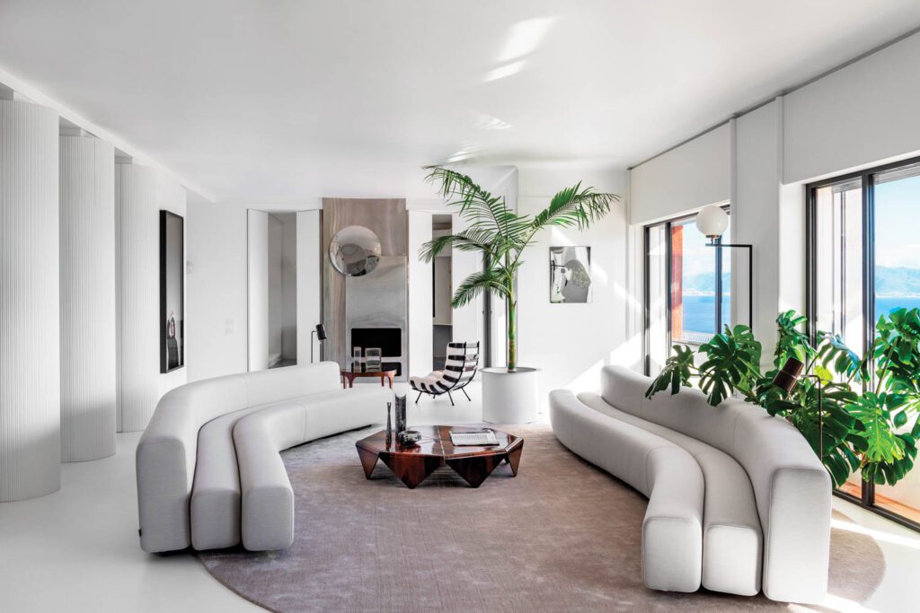 The vintage steel fireplace at the far end of the living room was created by Robert Ascain in 1972; the floor lamp near the window is by Luigi Caccia Dominioni.