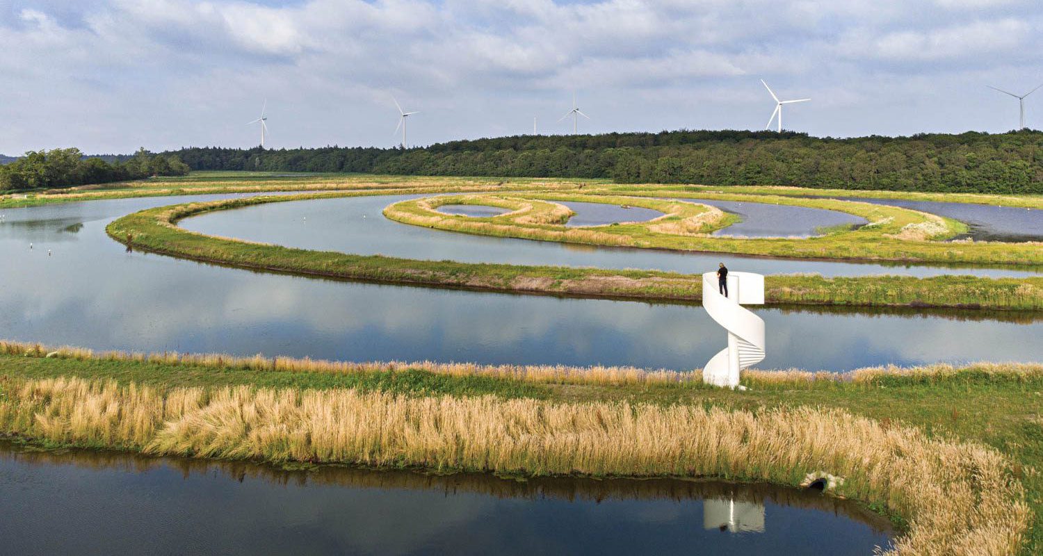 a person climbs the spiral staircase to look out over the earth ripple installation