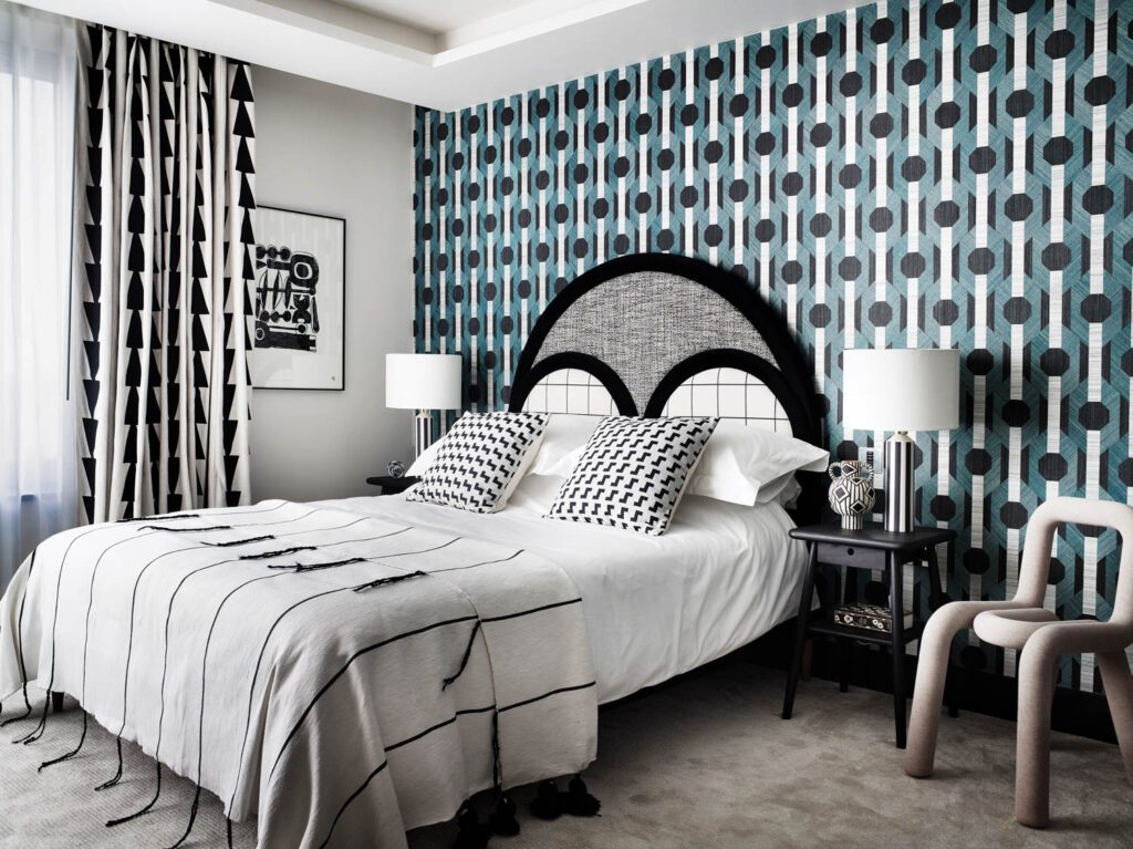 A graphic wallcovering accents the headboard wall in the second guest room, with a Bold chair by Moustache and a framed print by Karel Balas.