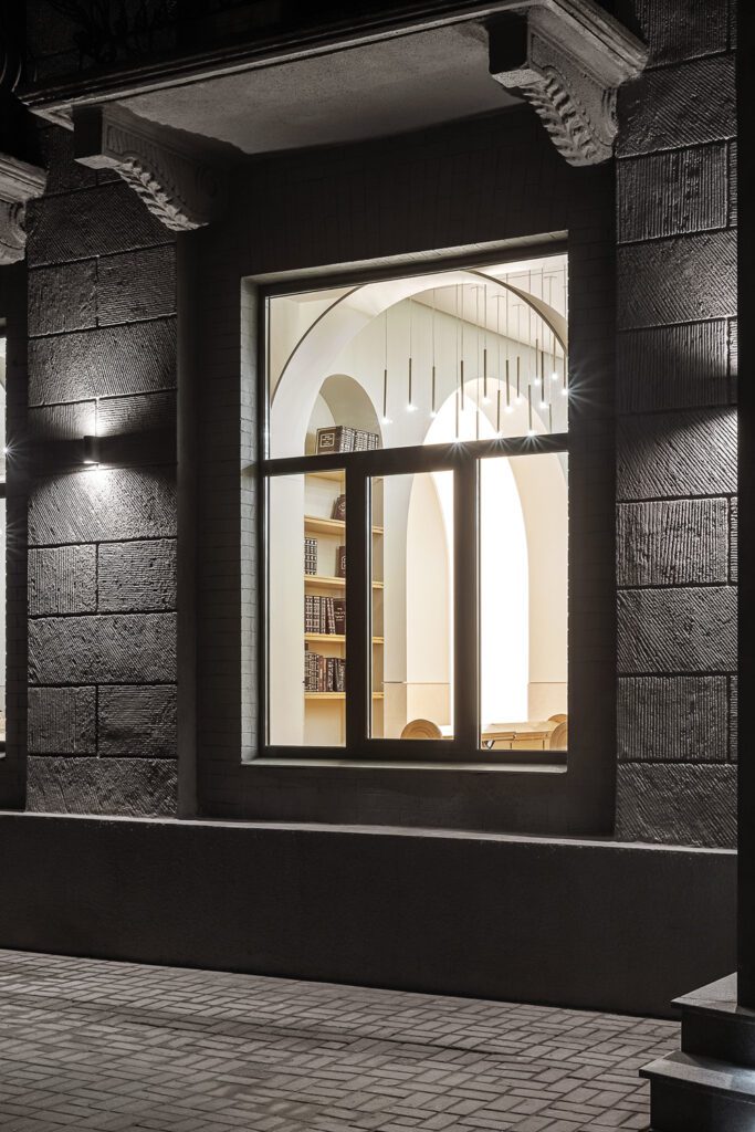 An illuminated window of the synagogue seen from outside at night. 