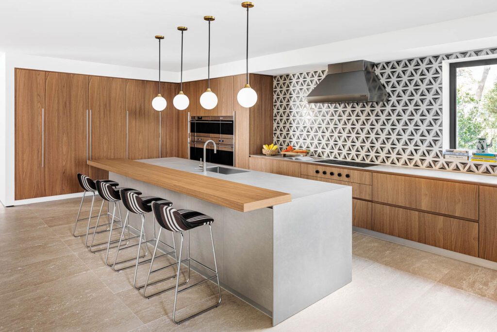 globular pendant lights hang above the kitchen island with black and white barstools underneath