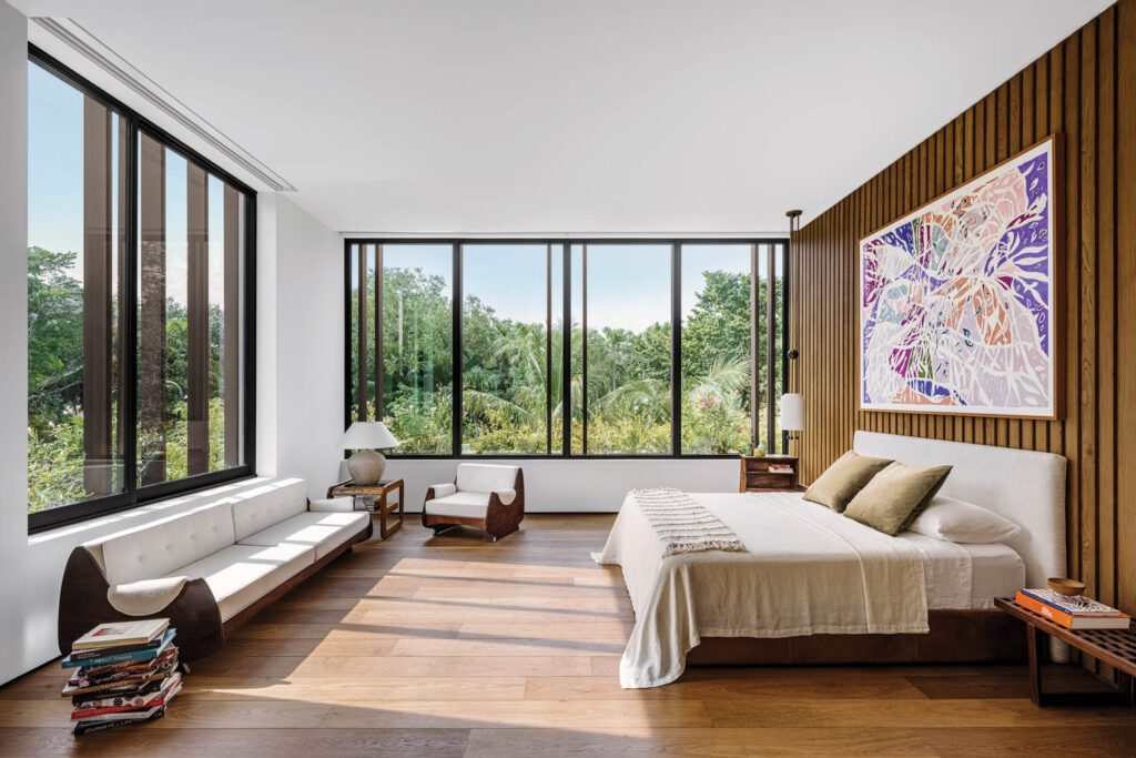 In the primary bedroom, light fixtures are by Apparatus Studio and the painting is by Marcia de Moraes; George Nelson benches serve as bedside tables. 