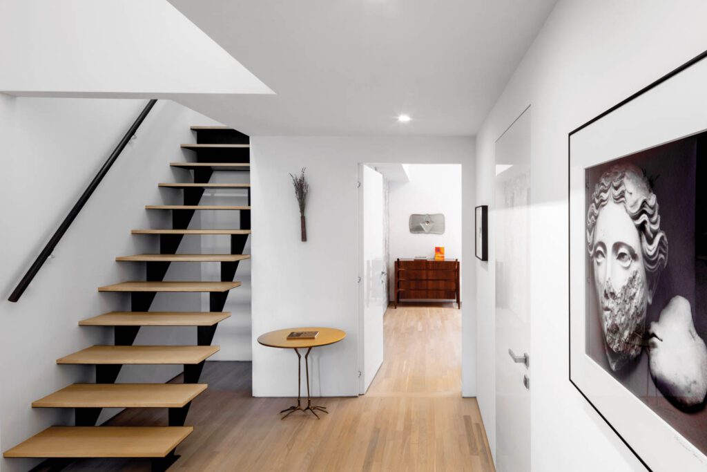 oak floors next to blackened-steel staircase leading to a mezzanine