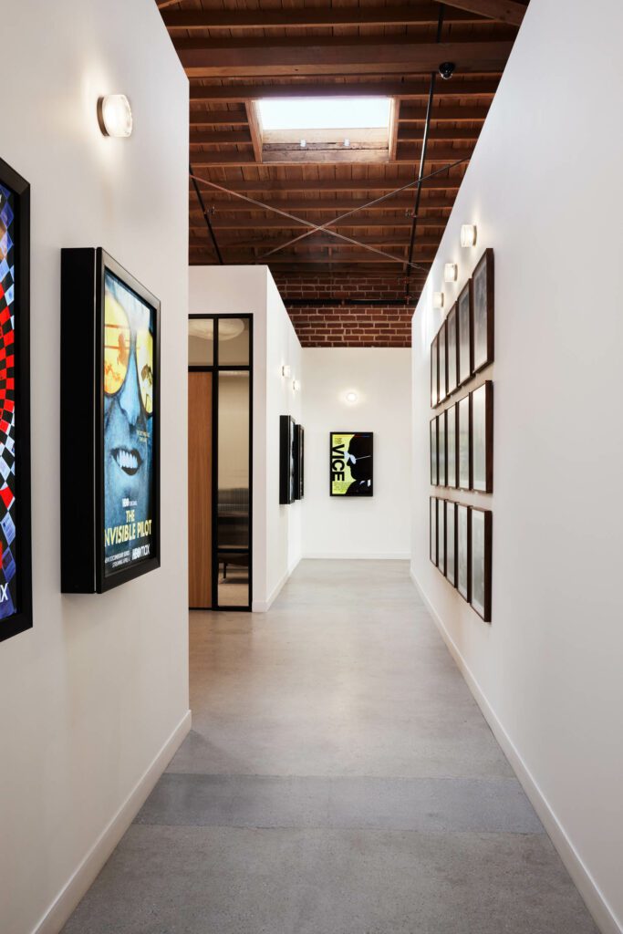 A concrete hallway culminates in a poster of the McKay-directed movie Vice surrounded by LEDs.