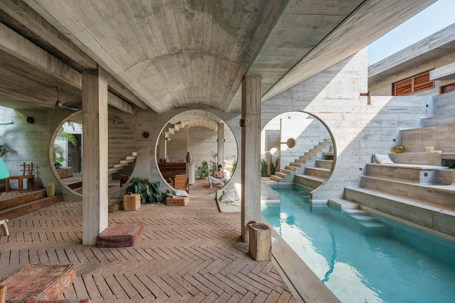 Circular apertures punched through the concrete walls connect the hotel’s different zones.