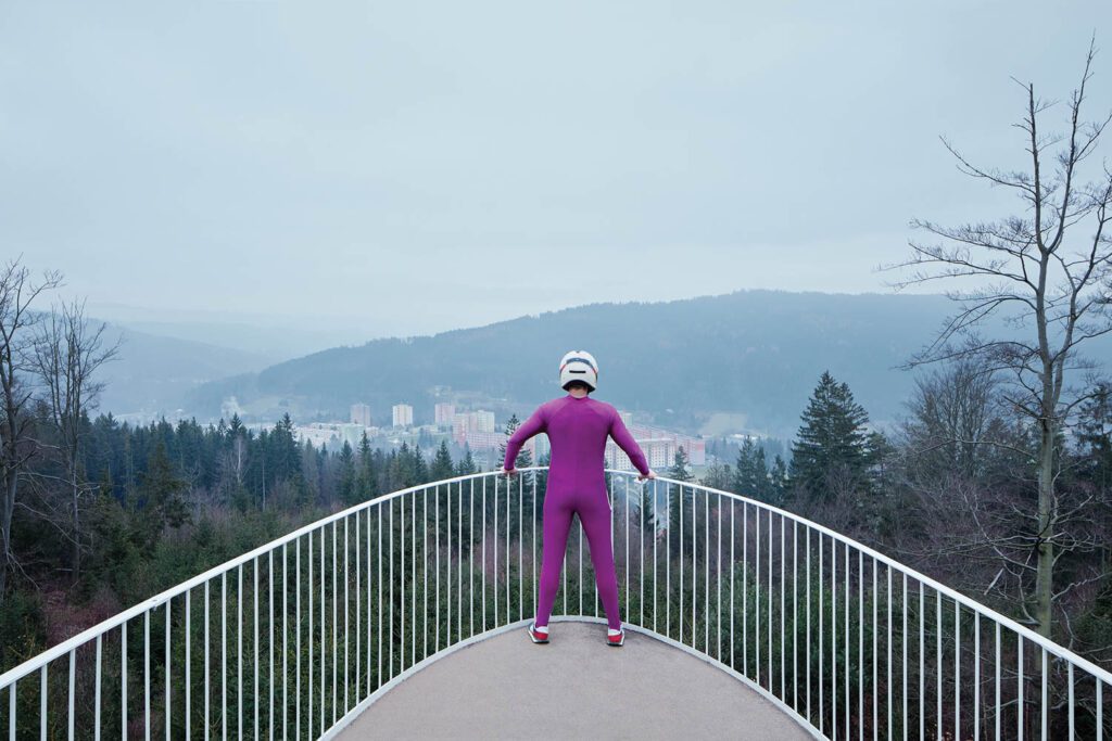 A man stands on the deck of the UFO-like building overlooking the mountain