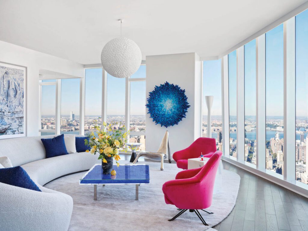 a light-filled living room with a curved white sofa and red arm chairs.