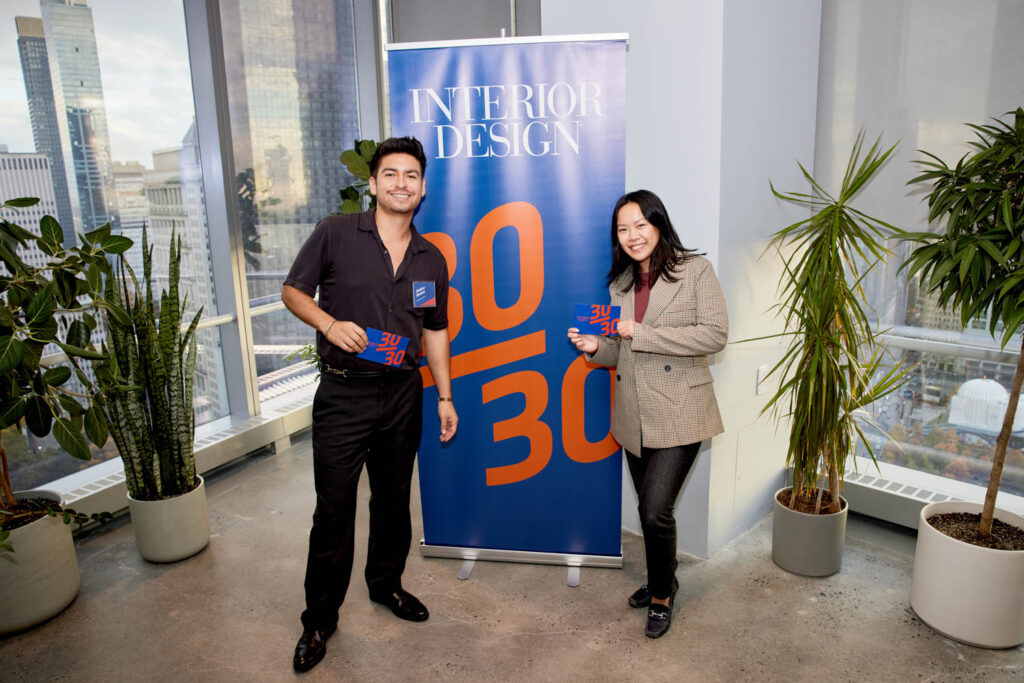 Two young designers stand in front of the 30/30 sign. 