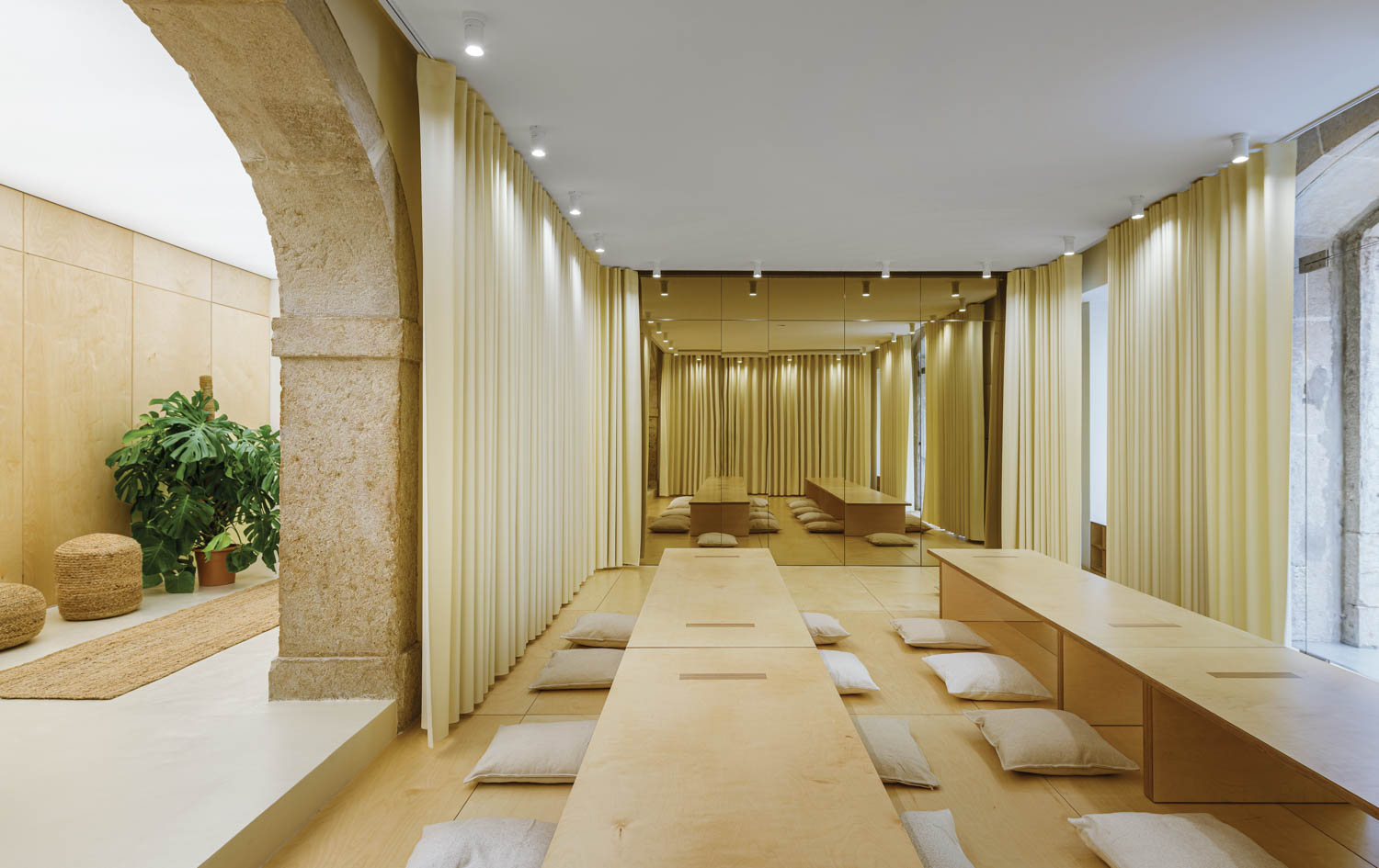 A curtained room with low wood tables and floor pillows