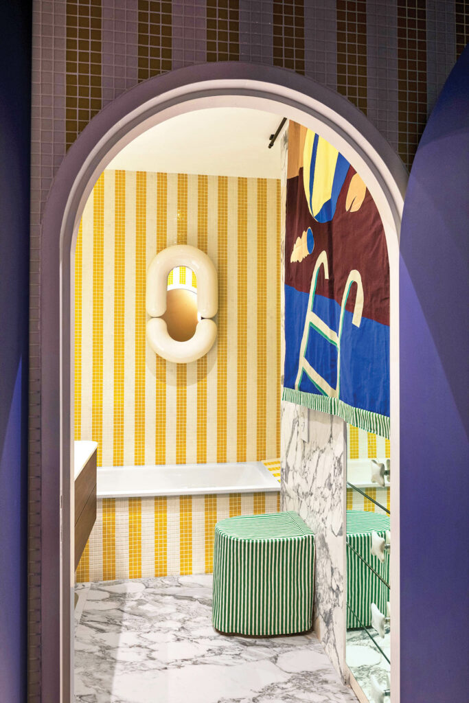 a bathroom with yellow and white striped walls and a patchwork curtain