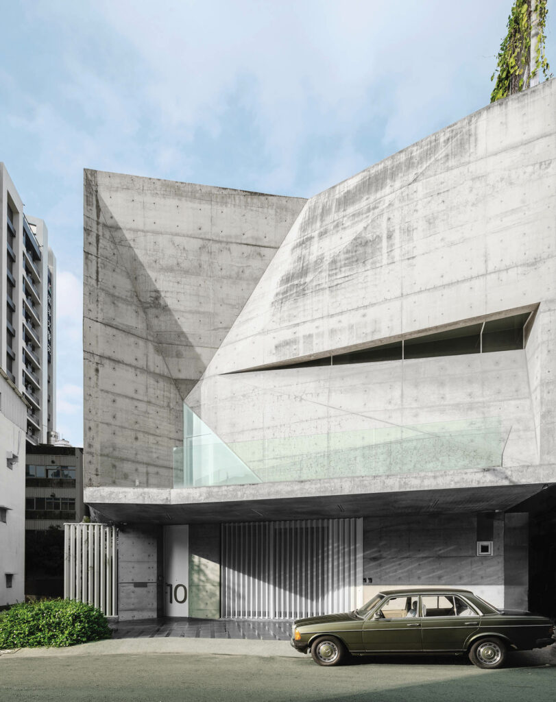 a car sits in front of a modern home with a concrete exterior