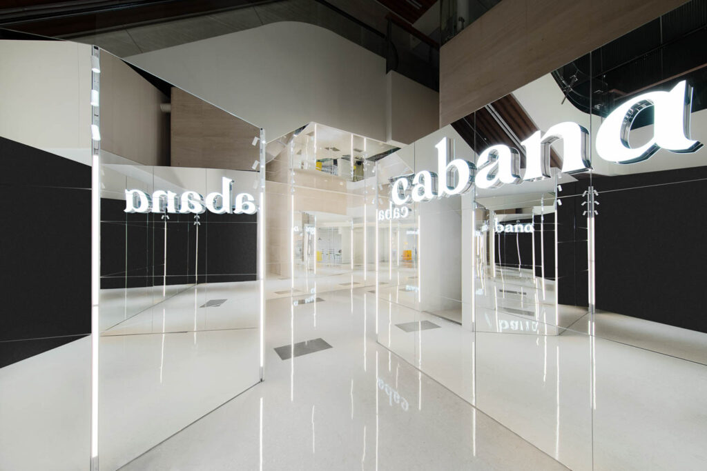 concrete flooring underneath mirrors reflecting a glowing Cabana sign