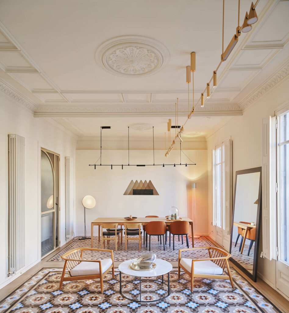 a dining table is seen behind a living room, all atop a geometric tile floor