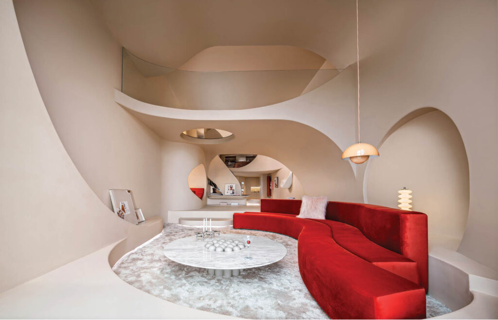 a red couch snakes around in a sunken living room area 