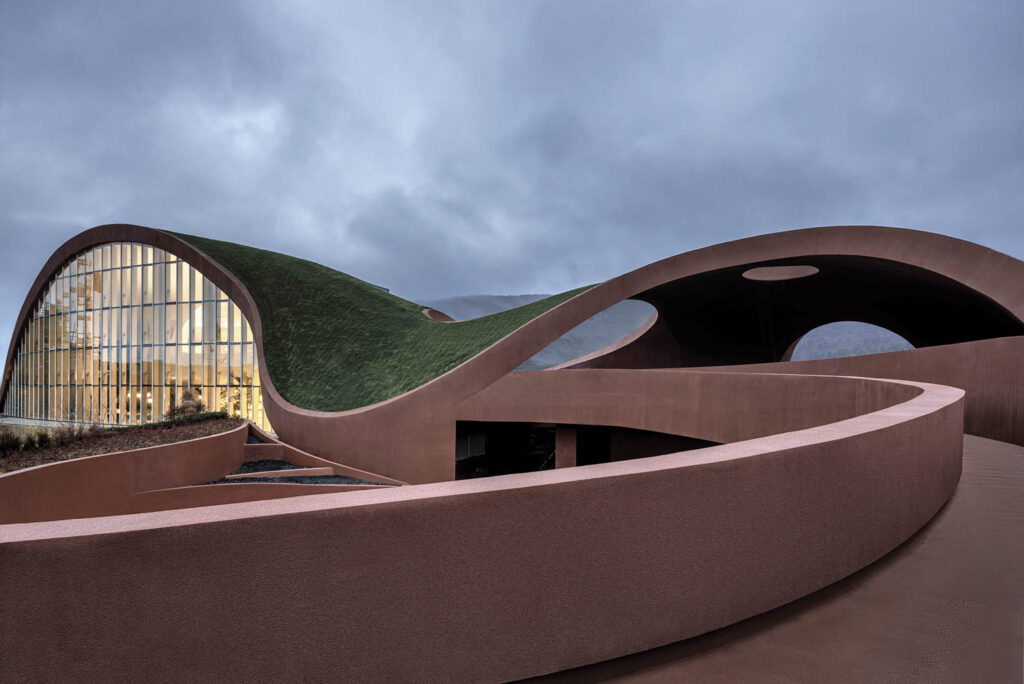 a shapely brown exterior of a building with lush grass atop it