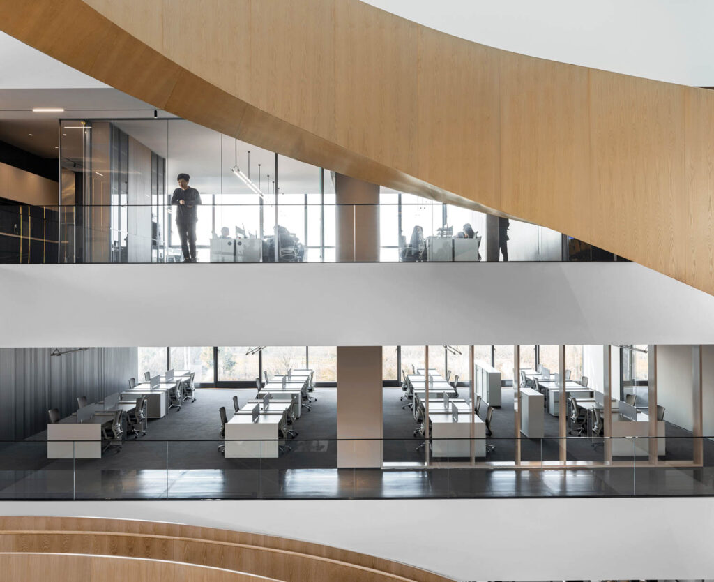 Open work areas at various levels of the building offer a view of the wooden staircase.