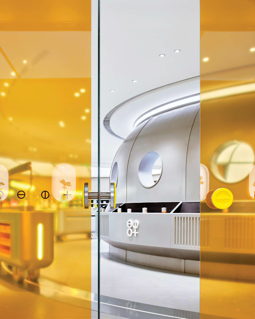 A spaceship-like space to sample cosmetics seen through yellow-tinted glass doors