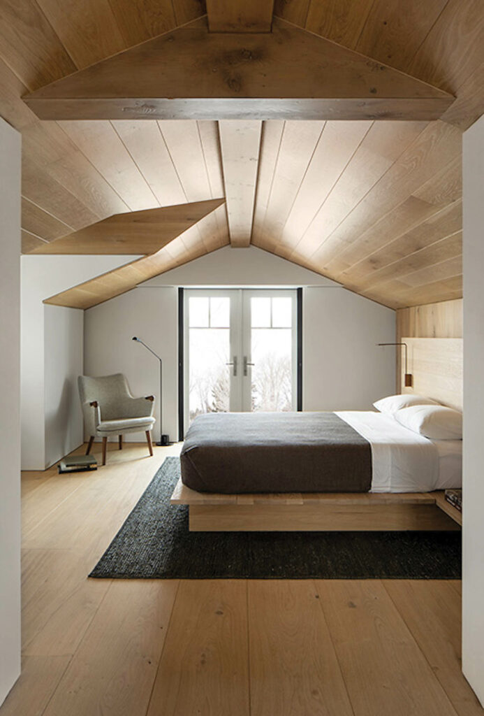 The bedrooms in the mountain retreat feature cedar plank ceilings and floors with minimalist furnishings. 