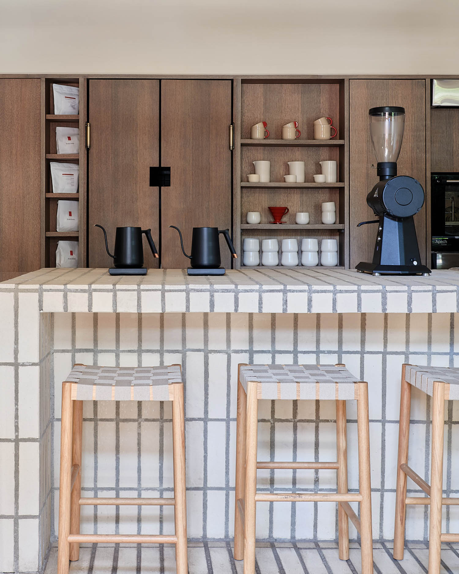 cream colored tiles line the countertop of a coffee shop, with bar stools lined up across the space