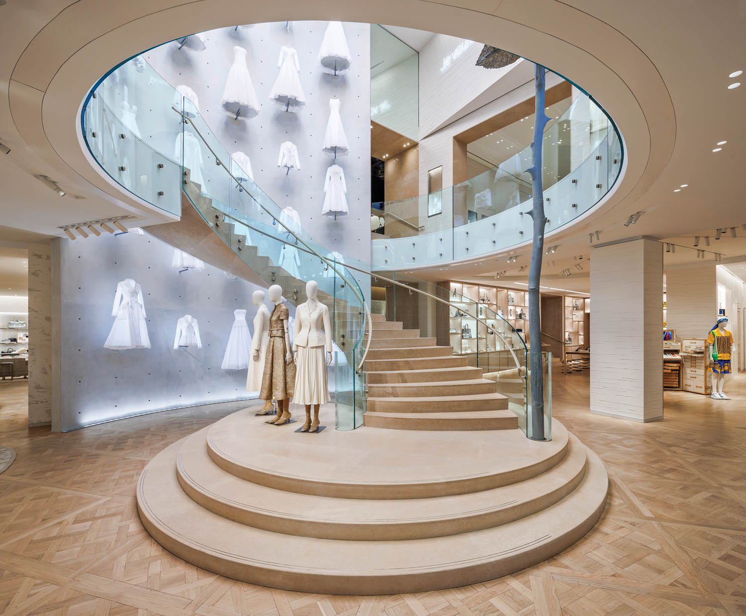 mannequins stand on the base of a winding staircase in a Dior boutique in Paris