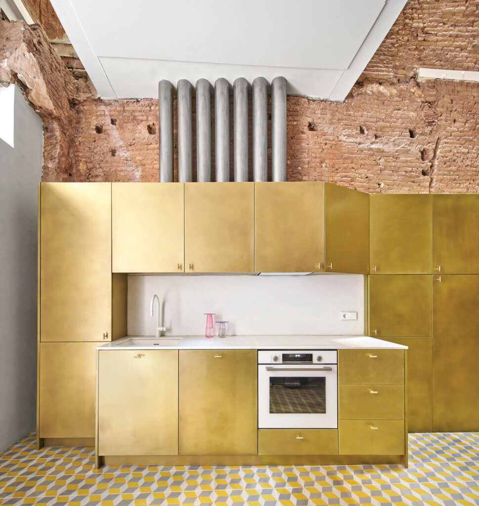 gold kitchen cabinetry against exposed brick walls