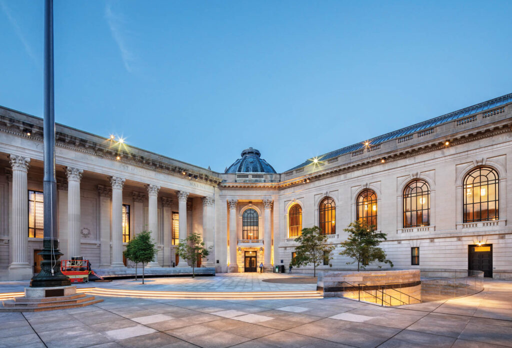 the exterior of the Schwarzman Center at Yale lit up at night, with grand columns and arch windows