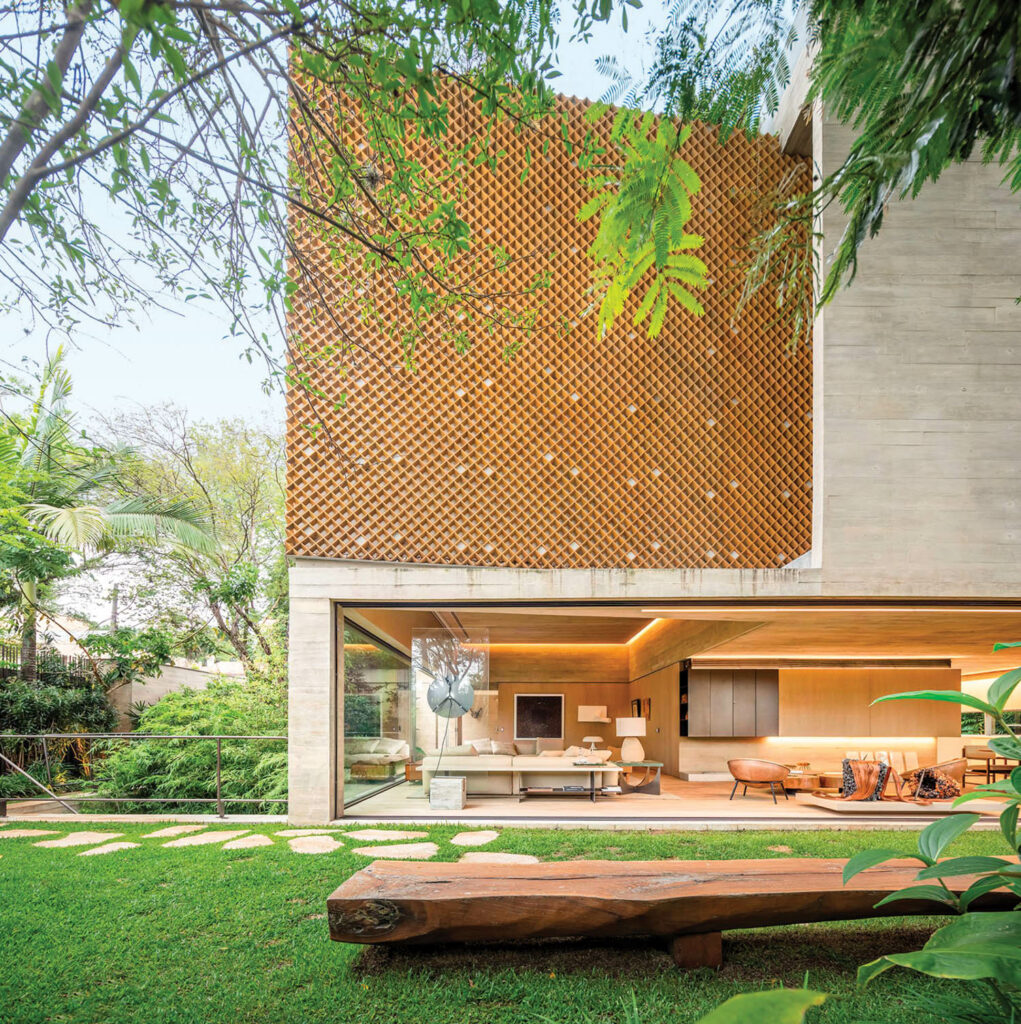 The exterior of the modernist home features a wooden lattice above the living area that opens to a grassy yard. 