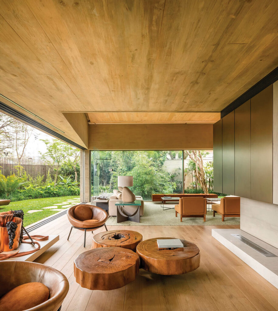 An indoor-outdoor living area opens into the yard and features a wooden coffee table with brown leather chairs.